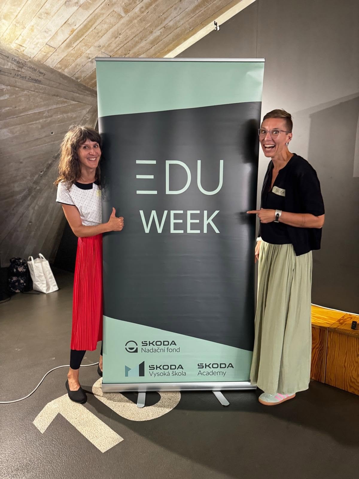 Two participants beside an EDU Week banner.