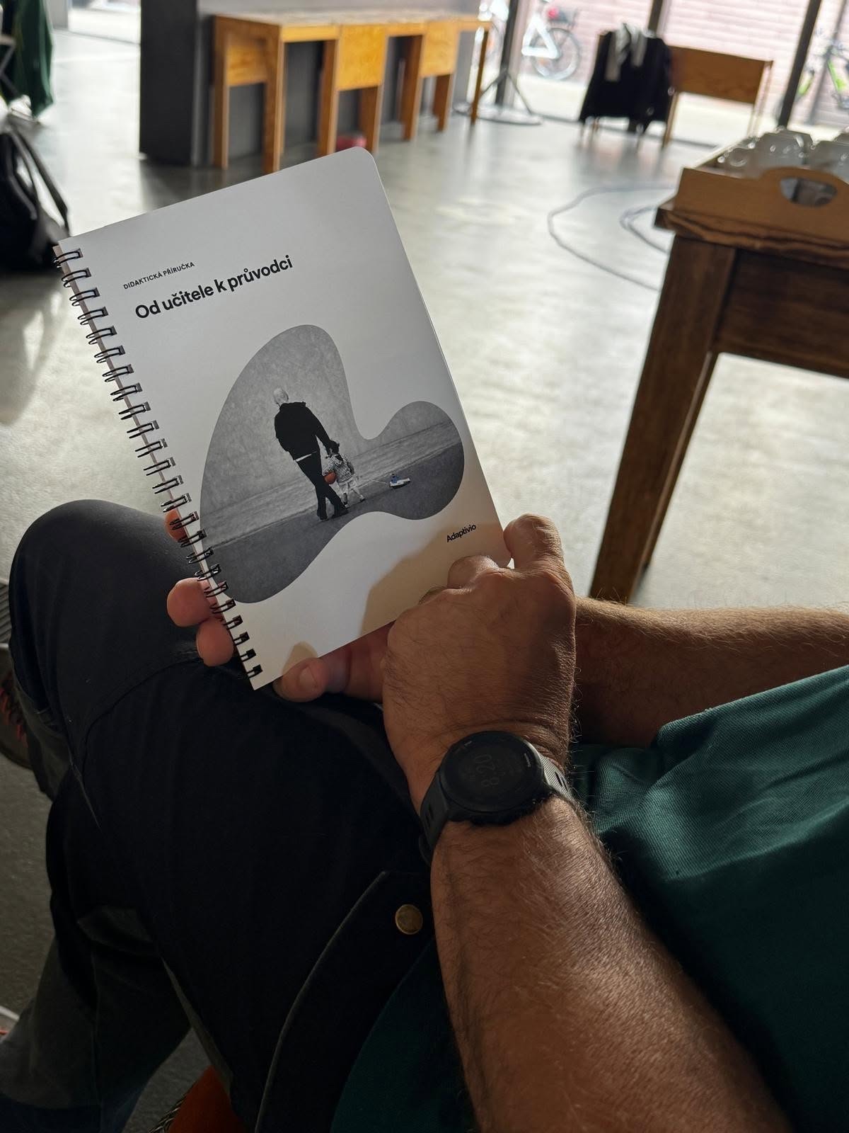 A participant holding the From Teacher to Guide teaching handbook.